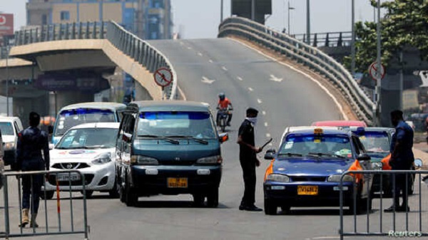 A police officer controls a car at a roadblock to restrict inter-city movement