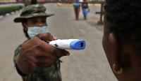 A member of the Nigerian army performs a temperature check on a visitor