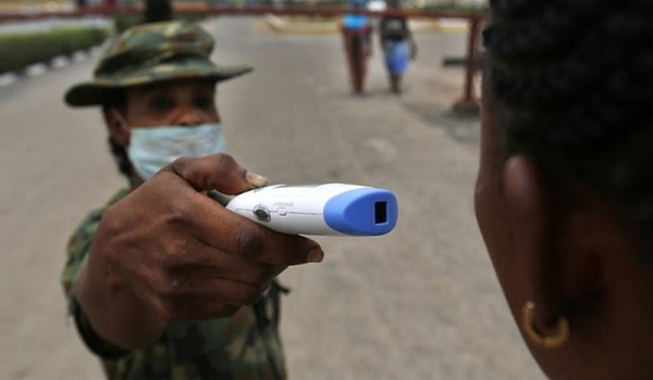 A member of the Nigerian army performs a temperature check on a visitor