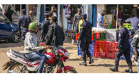 motorcyclist looks at police officers on patrol few minutes to the curfew (CYRIL NDEGEYA)