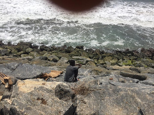 A resident of Ayisa using the sea defence as a place of convenience