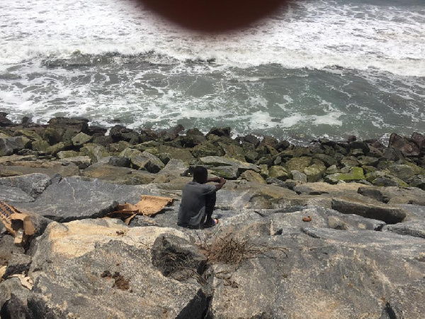 A resident of Ayisa using the sea defence as a place of convenience