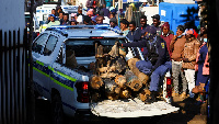 A police officer sits in the back of a police vehicle loaded with illegal mining equipment, after in