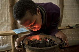 Lighting a charcoal fire for cooking, Rwanda