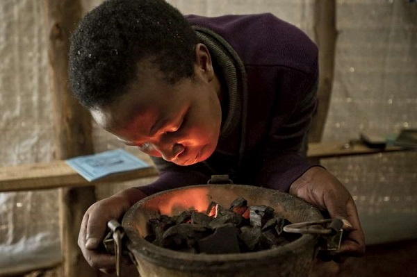 Lighting a charcoal fire for cooking, Rwanda