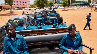 Police officers sit on the back of a pickup truck while they gather ahead of patrolling the streets