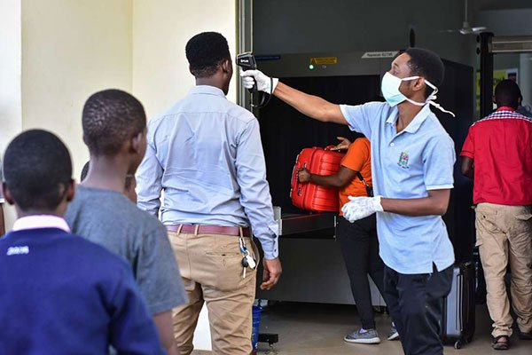 A worker checks the temperature of travelers at the border post with Kenya in Namanga, FILBERT RWEY