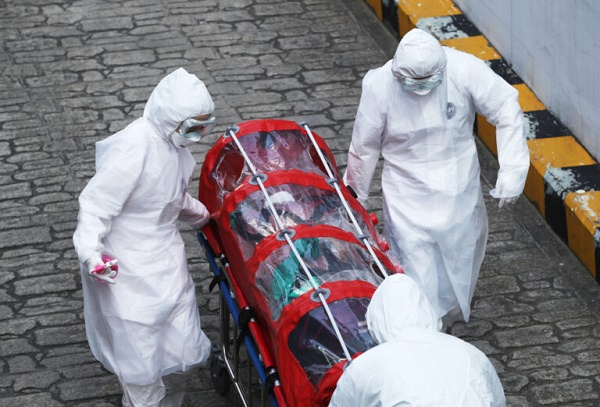 Medical staff members wearing protective gear with a patient infected with the coronavirus