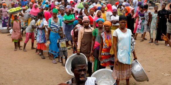 People wait to receive goods from volunteers to the underprivileged during the partial lockdown