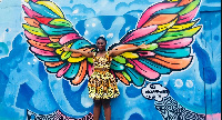 Chale Wote 2018; attendee poses in front of the wing mural by Ghanaian artist, Mohawudu