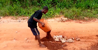 A young guy repairing one of the damaged roads in Odumase-Oterkporlu