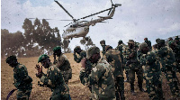 Soldiers protect their faces from projections when a helicopter lands in South Kivu Province