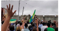 A military vehicle passes by people celebrating in Gabon after military officers announced coup