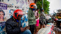 People using smartphones at a motorcycle taxis waiting area in Uganda