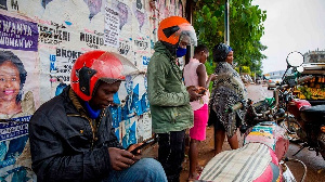 People using smartphones at a motorcycle taxis waiting area in Uganda