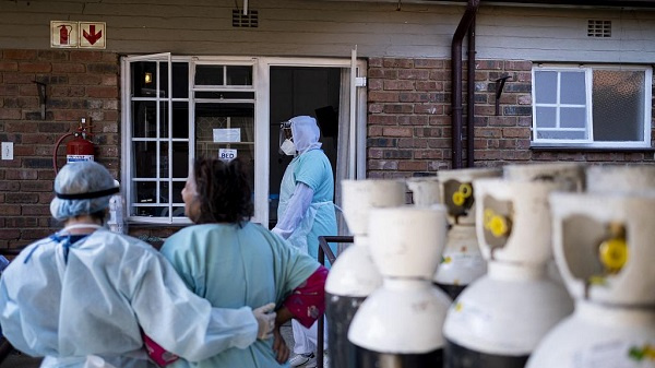 A health worker  helps a coronavirus patient back to her room in a non-profit coronavirus facility