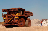 A worker signals to a Haul truck driver at Kumba Iron Ore