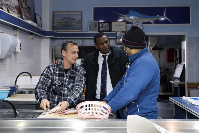 Hagabimana talks with two fishmongers on the island of Salamina [File: Louiza Vradi/Reuters]