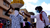 A Uganda Red Cross volunteer conducts a temperature check on a vendor in Kampala