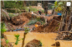 An illegal artisanal miner searches for gold in an excavated pit at the Prestea-Huni Valley