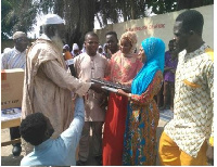 Headmaster of the school receiving the items from the old students