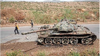 Farmers walk next to a tank abandoned along the road in Dansa, southwest of Mekele