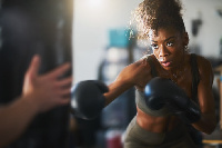 African-American woman striking a punching bag in a home gym in fighting stance