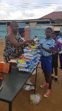 Appianyinasehene of Juabeng, Nana Kwanin Kwanfo II presenting a book to one of the students