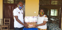 Madam Charity A.F. Dwommoh (DCE) handing the items to Mr. Mark Domah, Education Director.