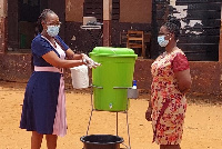 Madam Agartha Adra demonstrating how to wash hands with soap and water