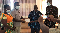 Stephen Yakubu presenting the cheque to Mr Adda's family