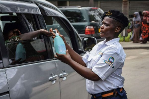 A security officer dispenses chlorinated water to a passenger at Muhimbili National Hospital in Dar