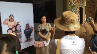 China's Ambassador to Ghana, Sun Baohong, poses with a cartoon criticizing China's role in Africa