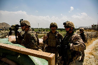 U.S. Marines and German service member watch an entry gate during an evacuation