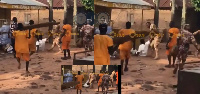 Men in prison officer uniform, and some inmates beating up a man in white