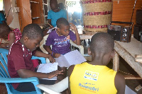 Pupils in Njeru Central Division listen and take notes during a radio lesson