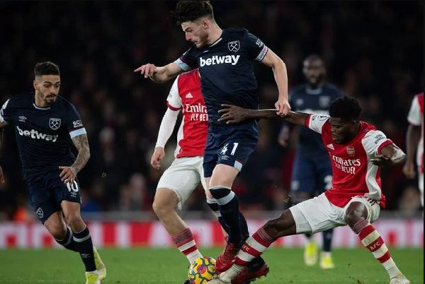 A photo of Thomas Partey challenging Declan Rice for a ball