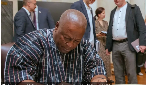 Mahama signs a copy of the Russian translation of his autobiography at the book launch in Moscow (J