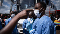 A staff of the Rwanda Biomedical Center (RBC) screens passengers at a bus station in Kigali,| AFP