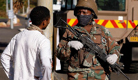 A soldier stands guard as police members check vehicles at the start of a 21 day nationwide lockdown