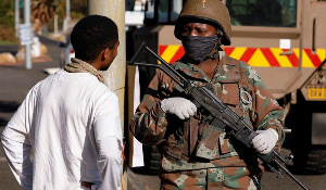 A soldier stands guard as police members check vehicles at the start of a 21 day nationwide lockdown