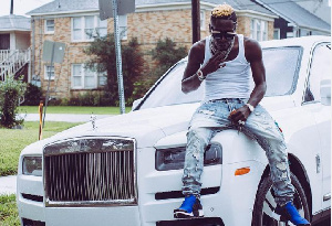 Shatta Wale sitting on the Rolls Royce