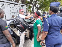 Atule Happy Atipoka watches her colleague being whisked away by the police