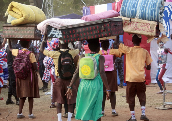 Some high school students on their way to school with luggages