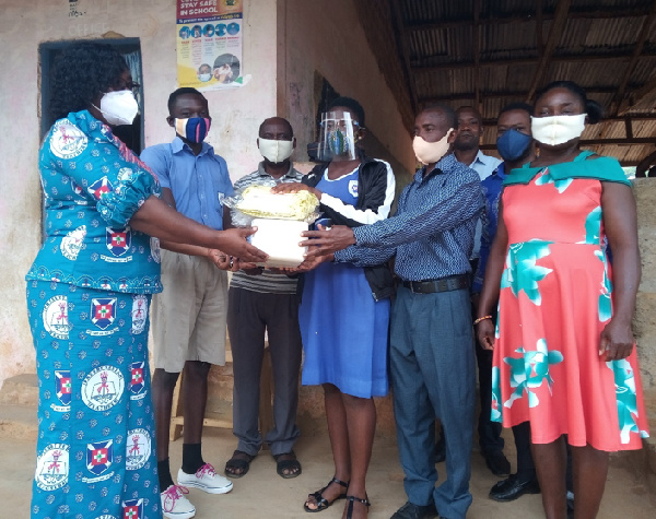 Headmaster, Akpalu (sandwiched by the students) receiving PPEs from Presbyterian Education Unit