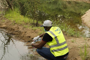 An Official From The FDA Takes A Sample Of The Gbele River