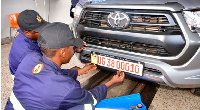 Mechanics fixing a new numberplate on a vehicle in Kampala, Uganda on November 1, 2023.