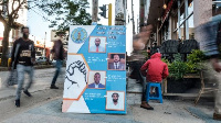 People walk past a campaign sign of a political party in the city of Mekele, Tigray