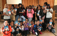 Havana Chapman-Edwards (kneeling extreme left) with friends holding the book 