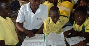 A coordinator assisting pupils in a reading activity